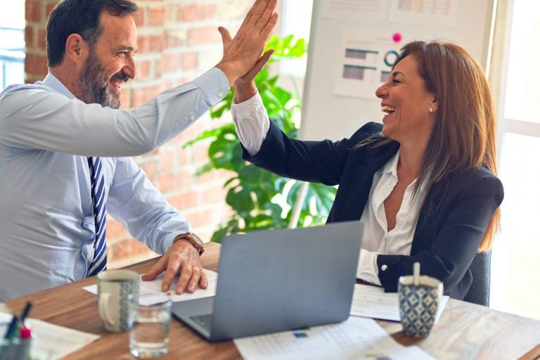 Zwei Geschäftspartner geben sich ein High-Five in einem modernen Büro.